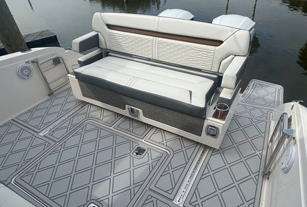 Interior view of a recreational boat cabin with cream and charcoal upholstered seating. The forward-facing convertible sofa