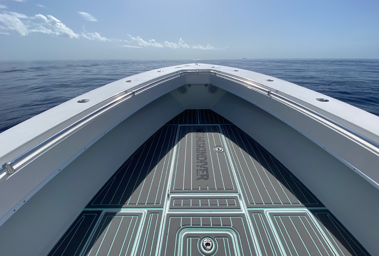 Forward-facing bow-on perspective of a fishing boat centered in frame, moving across open ocean...