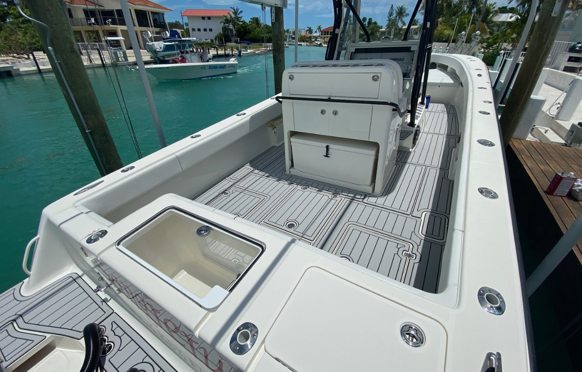 Wide-angle view of a white sport fishing boat's open cockpit area, showing gray non-slip flooring.