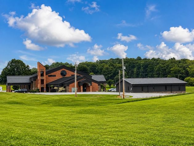 Brick-and-wood building on a grassy lawn under a bright blue sky with clouds