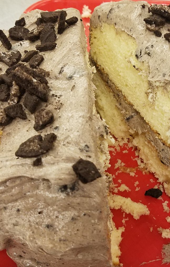 A slice of cake with oreos on top is on a red plate.