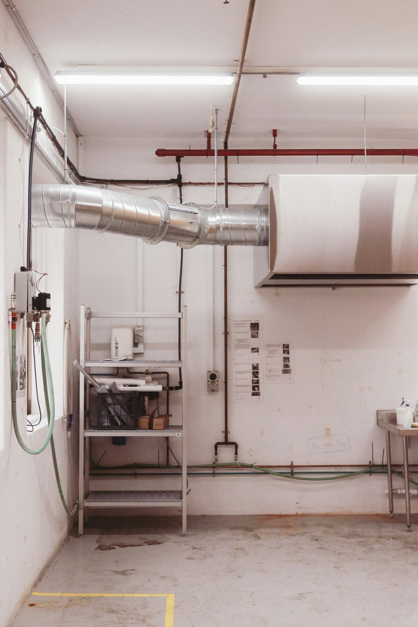 Overhead ducting and a stainless canopy in a commercial kitchen