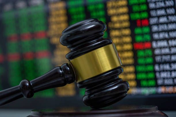A close up of a judge 's gavel in front of a stock chart