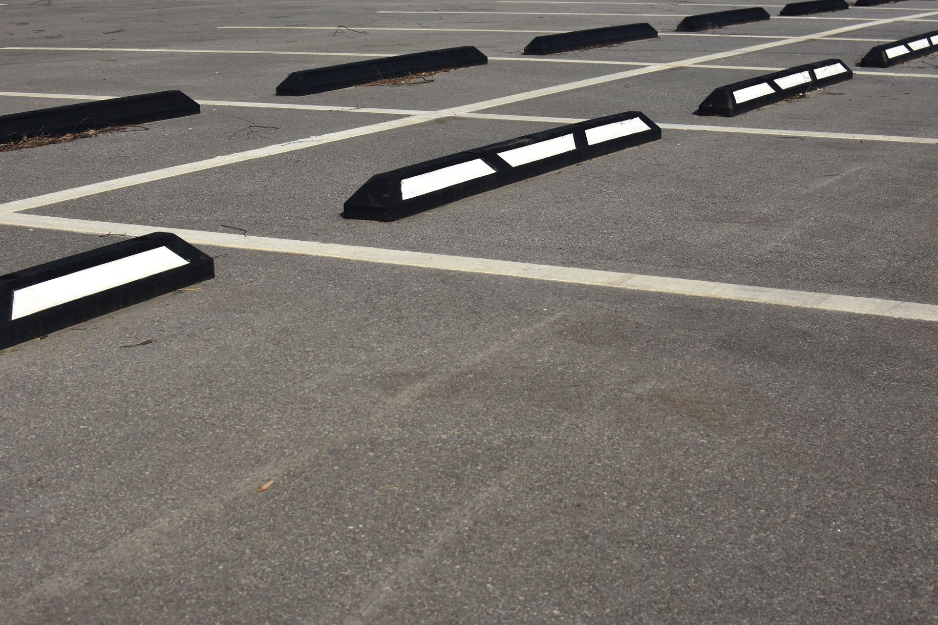 Parking lot with white-lined spaces and black parking stops with white reflective stripes.