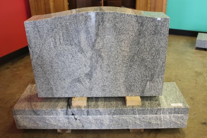 Two gray granite stone blocks stacked on a wooden pallet indoors