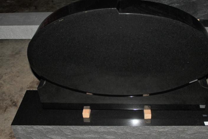 Black oval speaker or display on a dark base with small tan clips on a gray surface