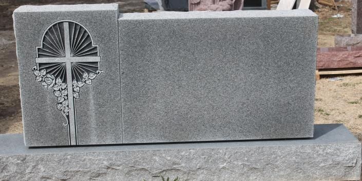 Gray granite memorial stone with a carved cross and floral design on the left side