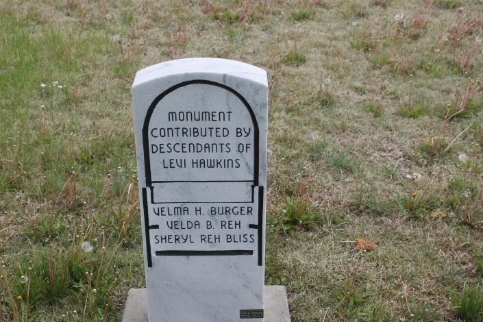 Gray memorial monument in a grassy field, honoring descendants of Lewis Haugh with engraved names.