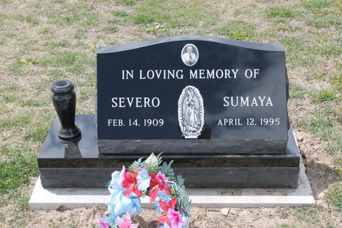 Black memorial headstone with flowers, reading “In loving memory of Severo and Sumaya.”
