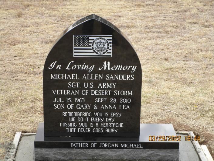 Black memorial headstone with U.S. flag, honoring Michael Allen Sanders and his service in Desert Storm.