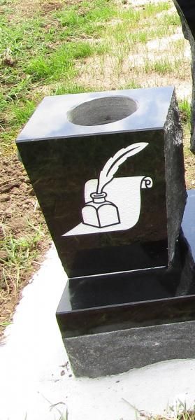 Black outdoor ashtray with a cigarette disposal symbol on a concrete base beside grass.
