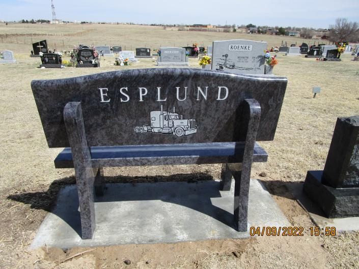 Esplund gravestone shaped like a bench in a cemetery, with a Bible engraving and open field background