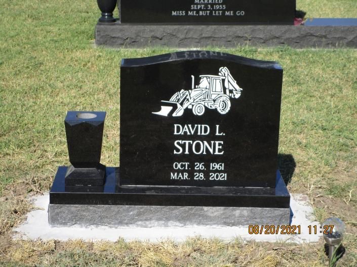 Black granite gravestone in a grassy cemetery, engraved with the name David J. Stone.