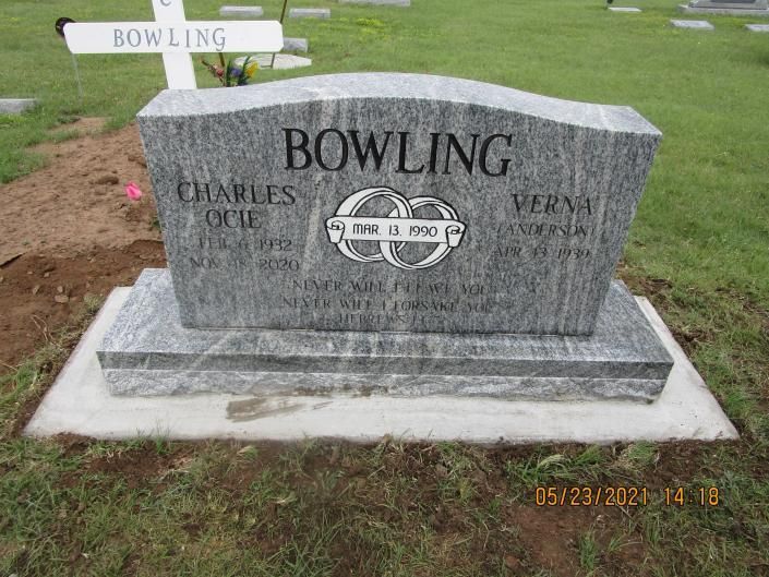 Gray granite bowling memorial stone with engraved bowling pin and ball in a grassy cemetery.