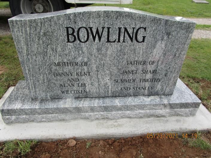 Bowling family gravestone in a grassy cemetery, with engraved names on gray stone.