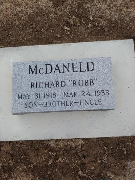 McDaneld grave marker on dirt, inscribed “Richard ‘Rob’,” with birth and death dates and “son-brother-uncle”