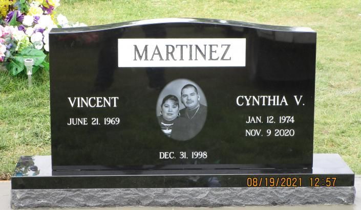 Black granite Martinez gravestone with oval portrait and engraved names, set on a cemetery lawn.
