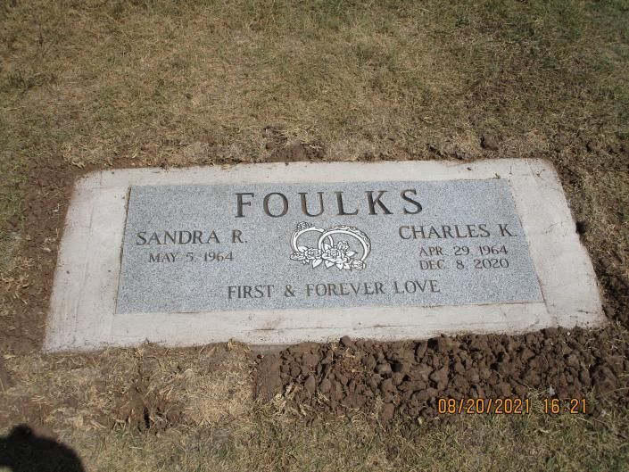 Gravestone on grass engraved “FOULKS” with names Sandra R. and Charles B. Foulks and “First & Forever Love”