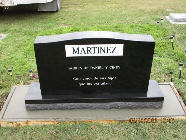 Marble grave marker with “MARTINEZ” engraved, standing on a grassy plot.