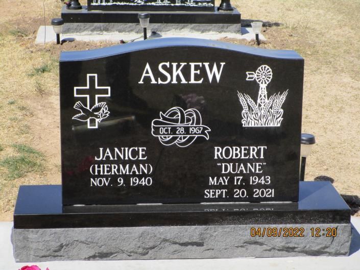 Black granite double gravestone reading ASKEW with names Janice and Robert “Duane” in a cemetery.