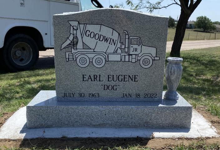 Gravestone with truck engraving and the name “Earl Eugene” in a sunny cemetery setting