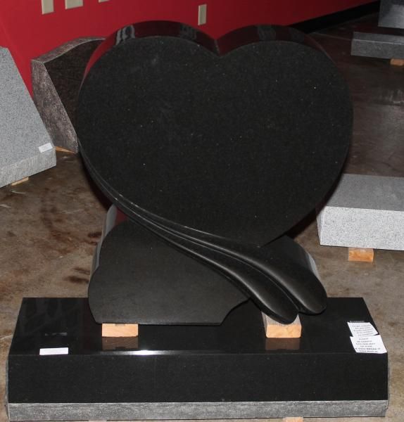 Black heart-shaped stone sculpture on a black base in a workshop or showroom setting