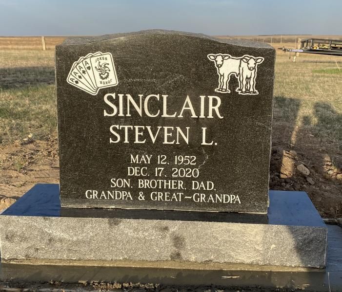 Black gravestone with military emblems for Steven L. Sinclair in a cemetery field.