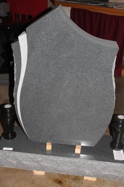 Gray upholstered shield-shaped panel displayed on a stand in a dark room