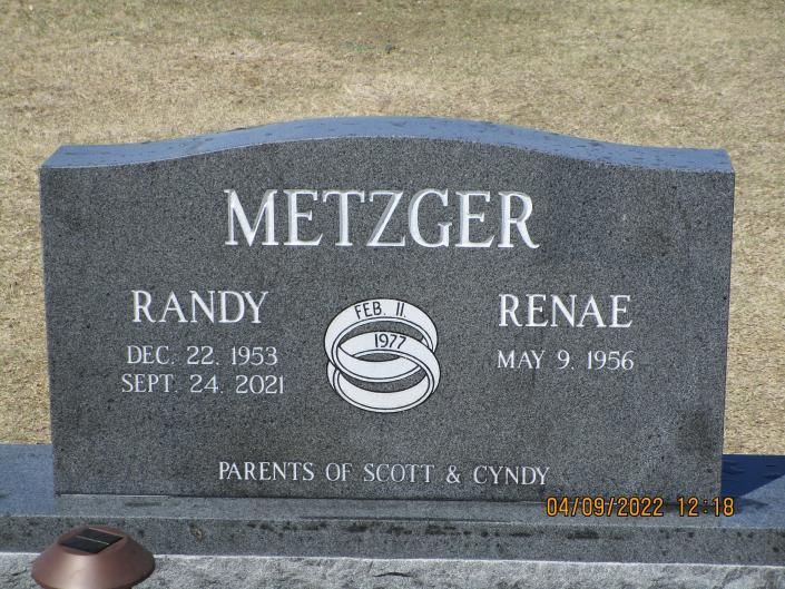 Gray gravestone with “METZGER” and the names Randy and Renae in a cemetery