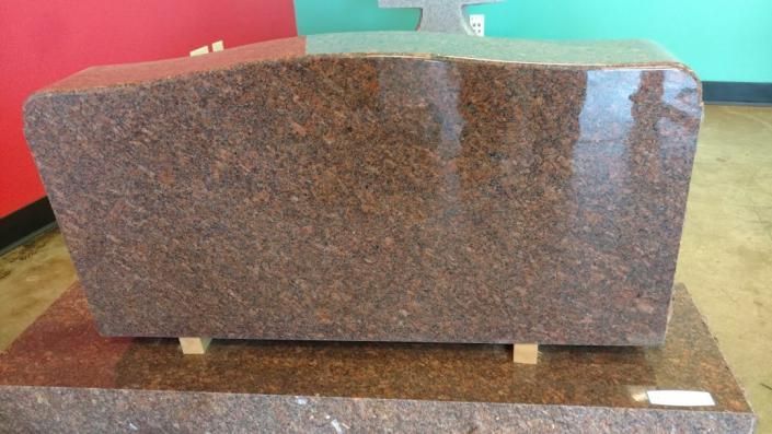 Large reddish-brown granite slab on a wooden pallet in a warehouse