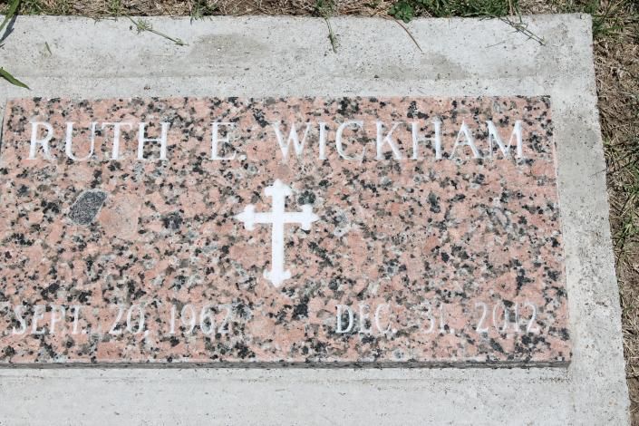 Gravestone with “RUTH E. WICKHAM” engraved in white on pink speckled stone, with a cross and flowers below