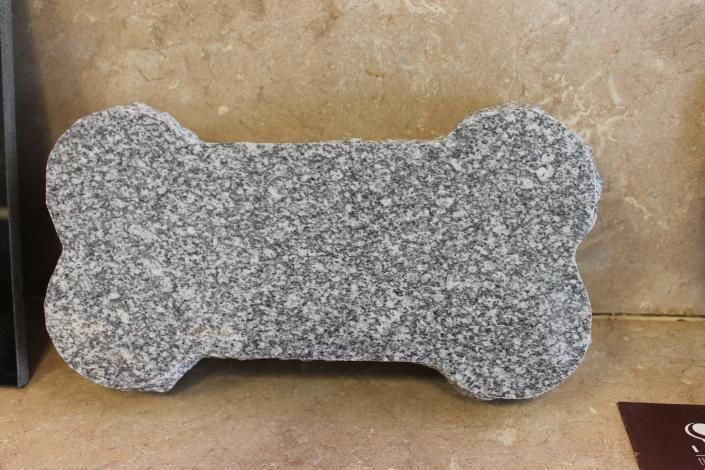 Bone-shaped gray speckled stone plaque against a tan wall