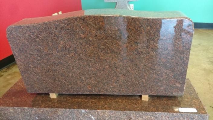 Brown speckled stone bench on a polished floor, with red and green panels in the background