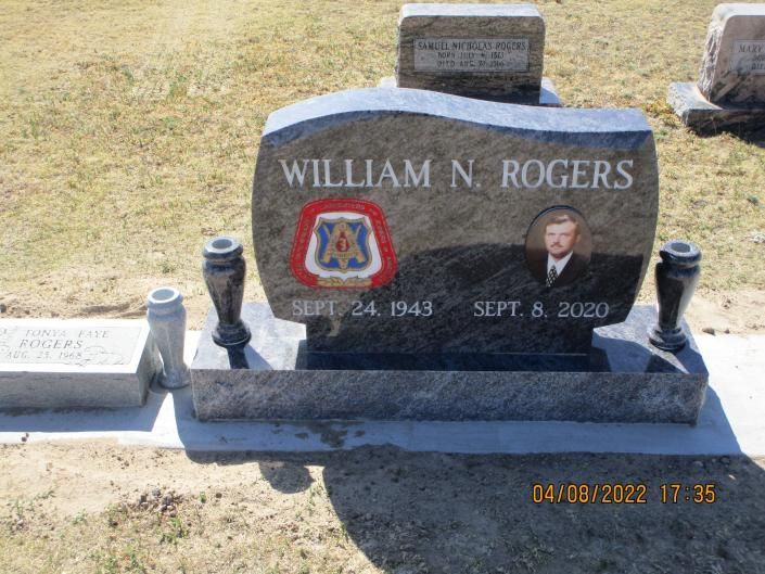 Gravestone for William N. Rogers with photos and military insignia in a cemetery