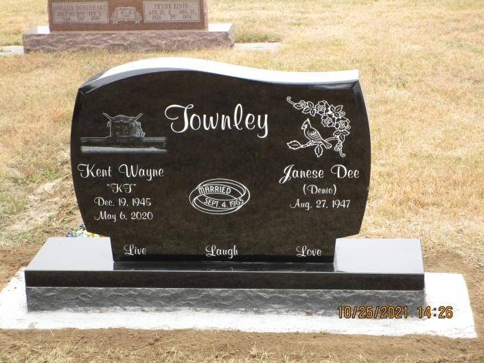 Black engraved headstone in a cemetery with the name “Towley” and floral decorations