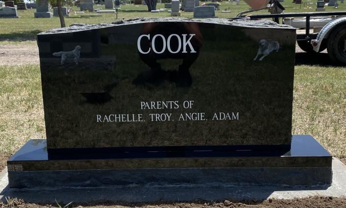 Black granite memorial bench engraved “COOK” with “Parents of Rachelle, Truj, Ange, Adam” in a cemetery