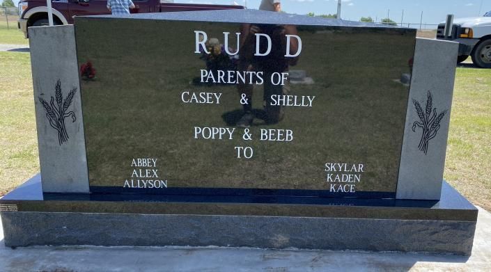 Rudd family gravestone in a cemetery, black stone with white lettering and a small deer engraving on the left.