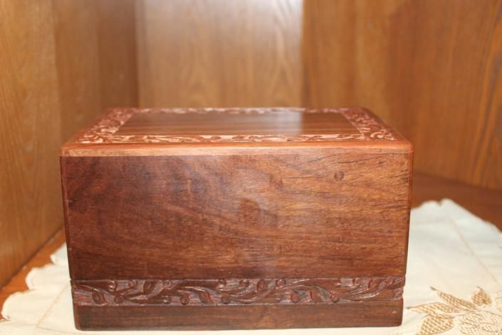 Small carved wooden box on a lace-covered surface against a wooden background