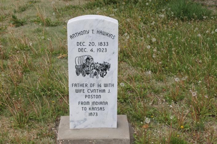 Small white gravestone in a grassy cemetery with an engraved floral design.