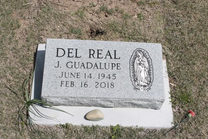 Gravestone for Del Real J. Guadalupe with engraved dates and religious plaque on grass