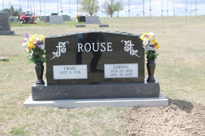 Black Rouse gravestone with flower vases in a cemetery field, honoring Craig and Loretta Rouse