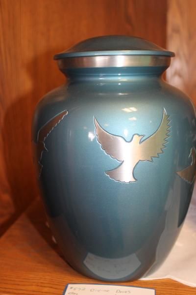 Blue urn with silver bird design on a wooden shelf