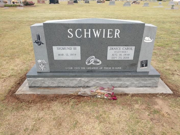Gray SCHWIER gravestone with white plaques in a cemetery, with flowers at the base.