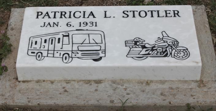Gravestone plaque reading “PATRICIA L. STOTLER” with a camper van and motorcycle engraving
