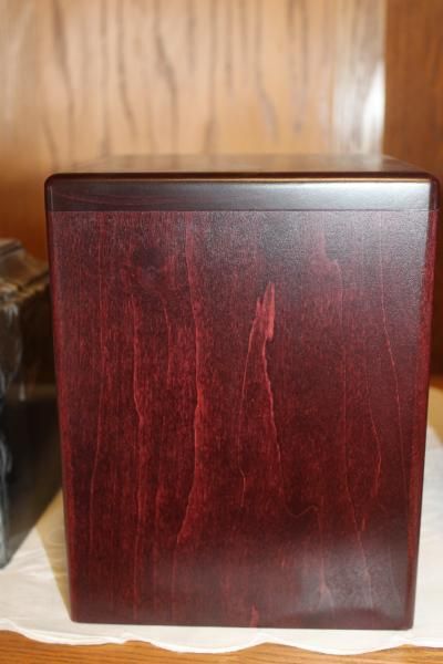Dark red wooden box or speaker cabinet against a wood-paneled background