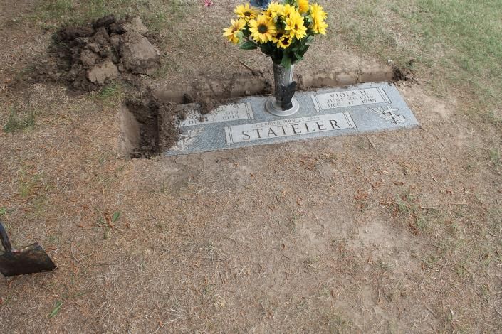 Gravestone with yellow flowers in a cemetery plot labeled “STATE 6B”