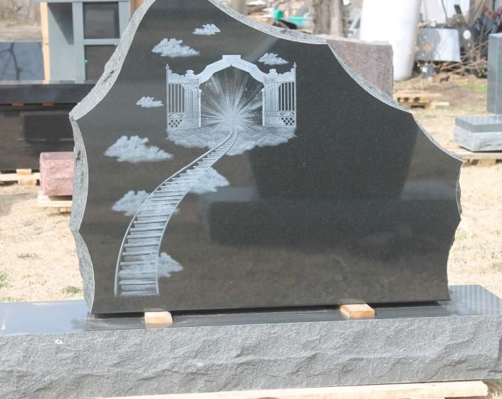 Black polished gravestone with etched staircase, clouds, and gazebo design in a cemetery workshop setting