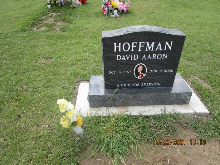 Black gravestone for David Aaron Hoffman on a grassy cemetery plot, with flowers nearby