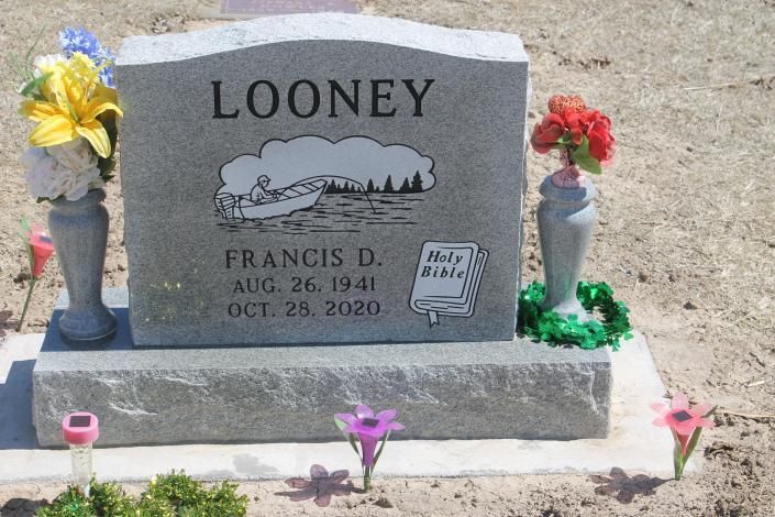 Gray Looney gravestone with flower vases and small memorial decorations in a cemetery