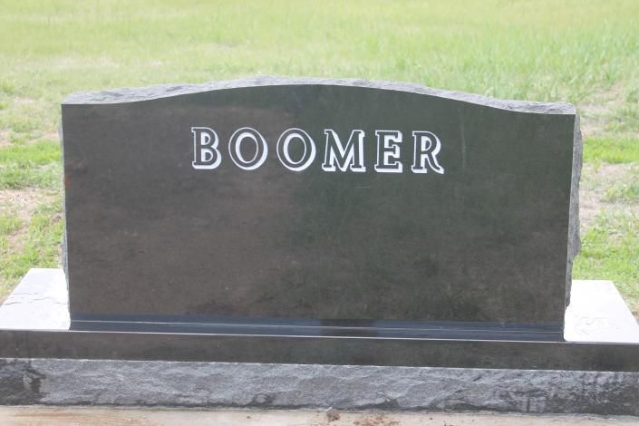 Gravestone with the name “BOOMER” engraved in white on a dark stone monument.